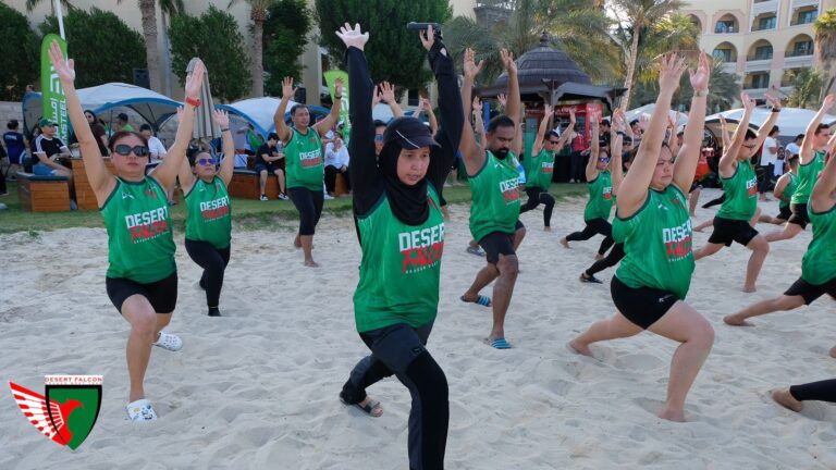 Desert Falcons dragon boat team stretching on the beach during warm-up.