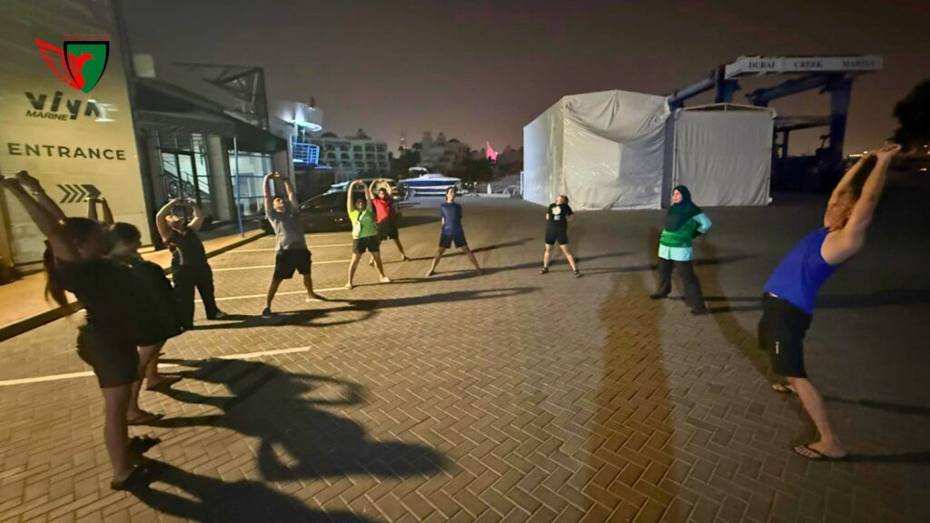 Desert Falcons paddlers performing warm-up exercises before entering the water.